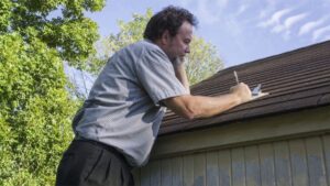 roof nail pops Roofing professional inspecting asphalt shingles for raised nails and fastening issues